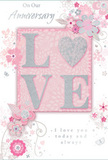 This anniversary card appears as a delicate celebration of enduring romance, suited to accompany flowers delivered throughout Forest Hill and the surrounding streets. The design is infused with soft pastel pinks and silvery greys, creating an atmosphere of treasured intimacy. At the very centre, the word LOVE is displayed in raised glitter, its soft shimmer inviting touch. The letter shapes are smooth and flowing, with the O suggested as a shimmering silver heart, adding a focal point of gentle sparkle that recalls streetlights glinting after dusk along London Road. Encircling this central motif, a ring of blush and mauve flowers opens across the card, their petals rendered with a watercolour softness. Fine, sweeping lines outline each blossom and connect them with slender vines, echoing the natural curves seen in an English spring garden or a thoughtfully arranged Forest Hill bouquet. Small flourishes-tiny petals, curling swirls, and subtle butterfly silhouettes-thread throughout the design, introducing a sense of movement and quiet playfulness. The background remains a calming blush pink, allowing the silver accents and pale blooms to stand out without clashing. Elegant script spells out On Our Anniversary and I love you today and always, the lettering understated yet full of warmth. The overall effect is one of gentle occasion: a keepsake that feels soft as a whisper but carries deep emotion. Like a carefully chosen arrangement from a local florist, this card honours a shared journey, wrapping sentiments of loyalty, tenderness, and gratitude into one beautifully balanced composition.